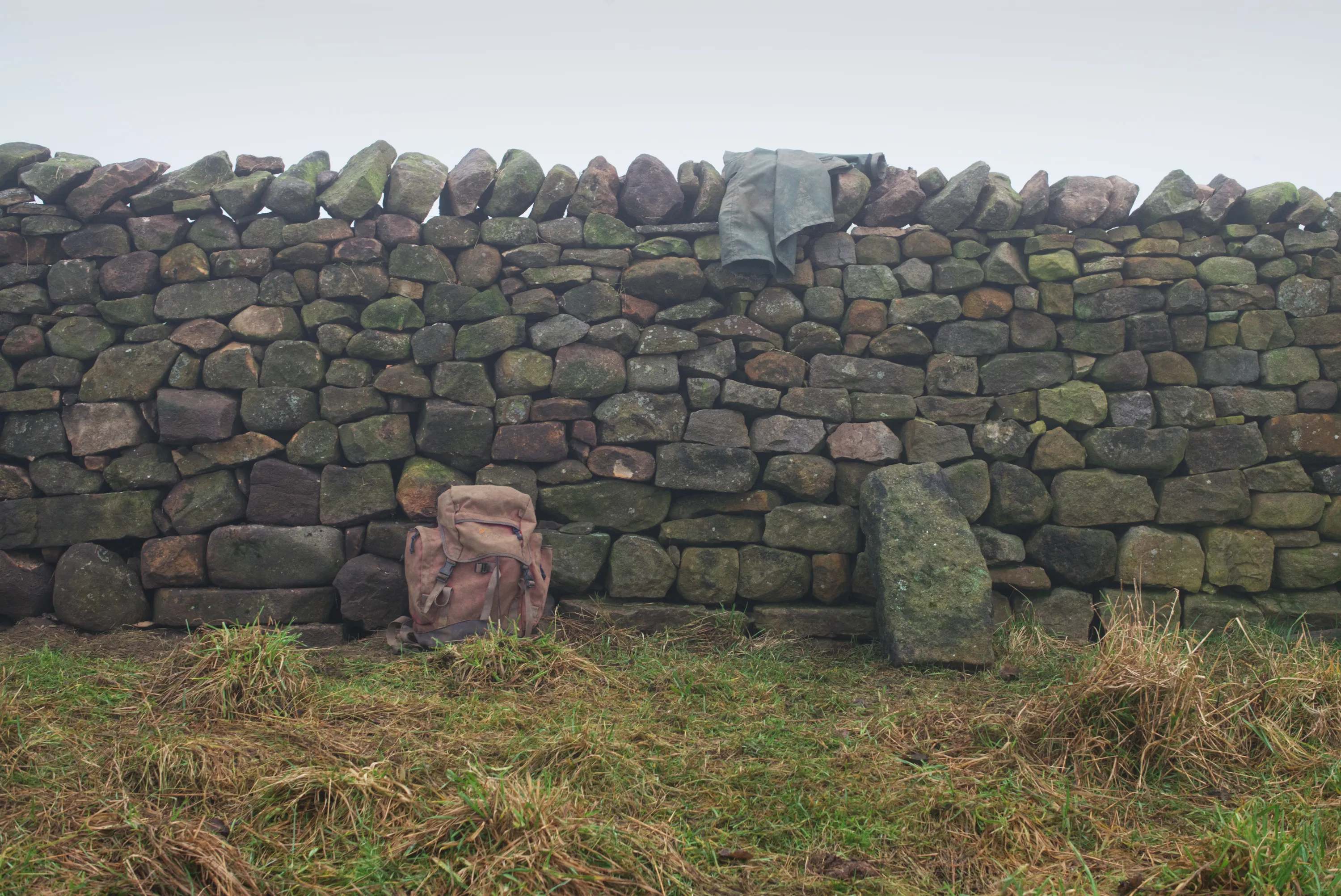 Completed section of dry stone wall with a jacket draped over the top