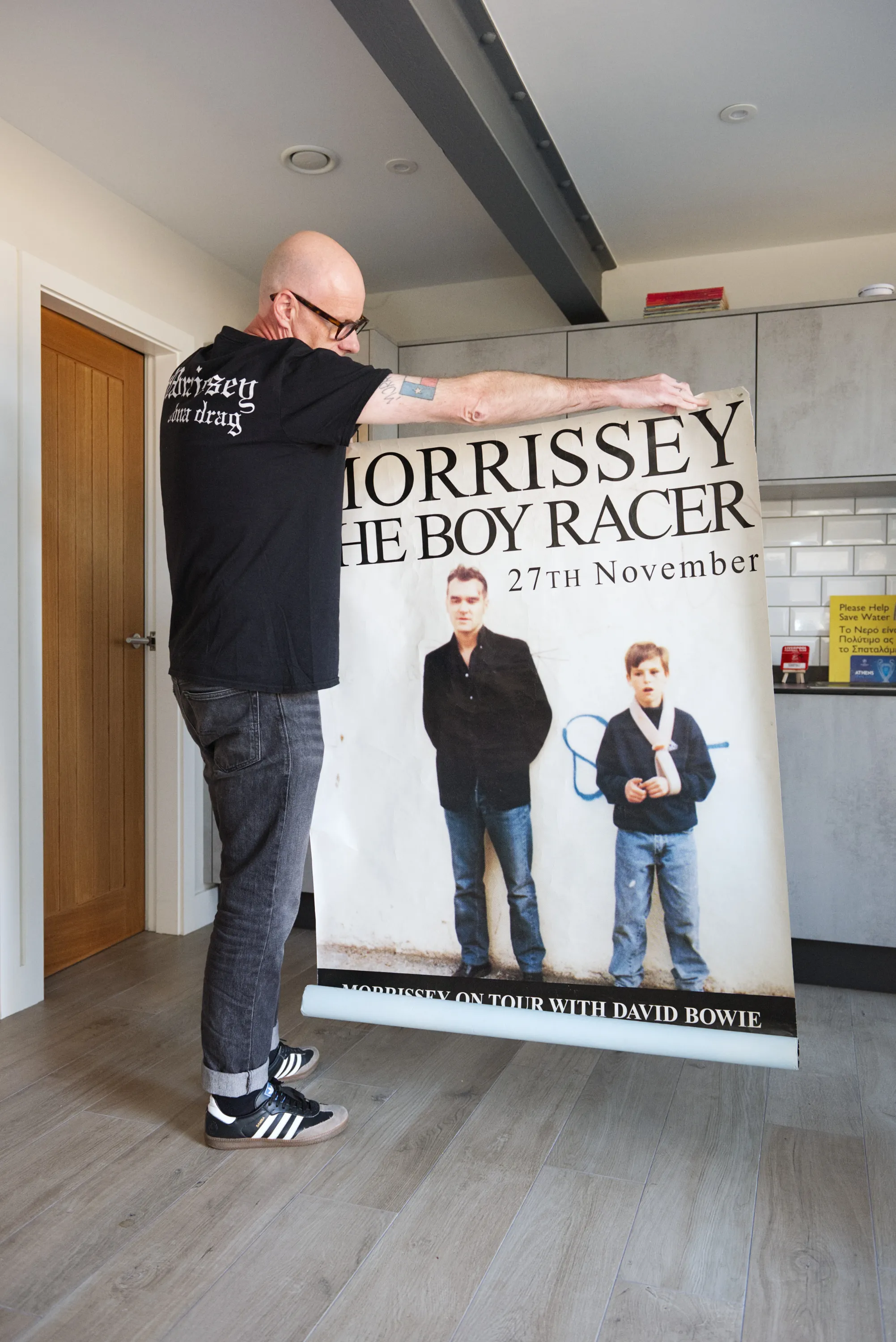 A collector holds up a large Morrissey concert poster reading The Boy Racer, 27th November — Morrissey on Tour with David Bowie