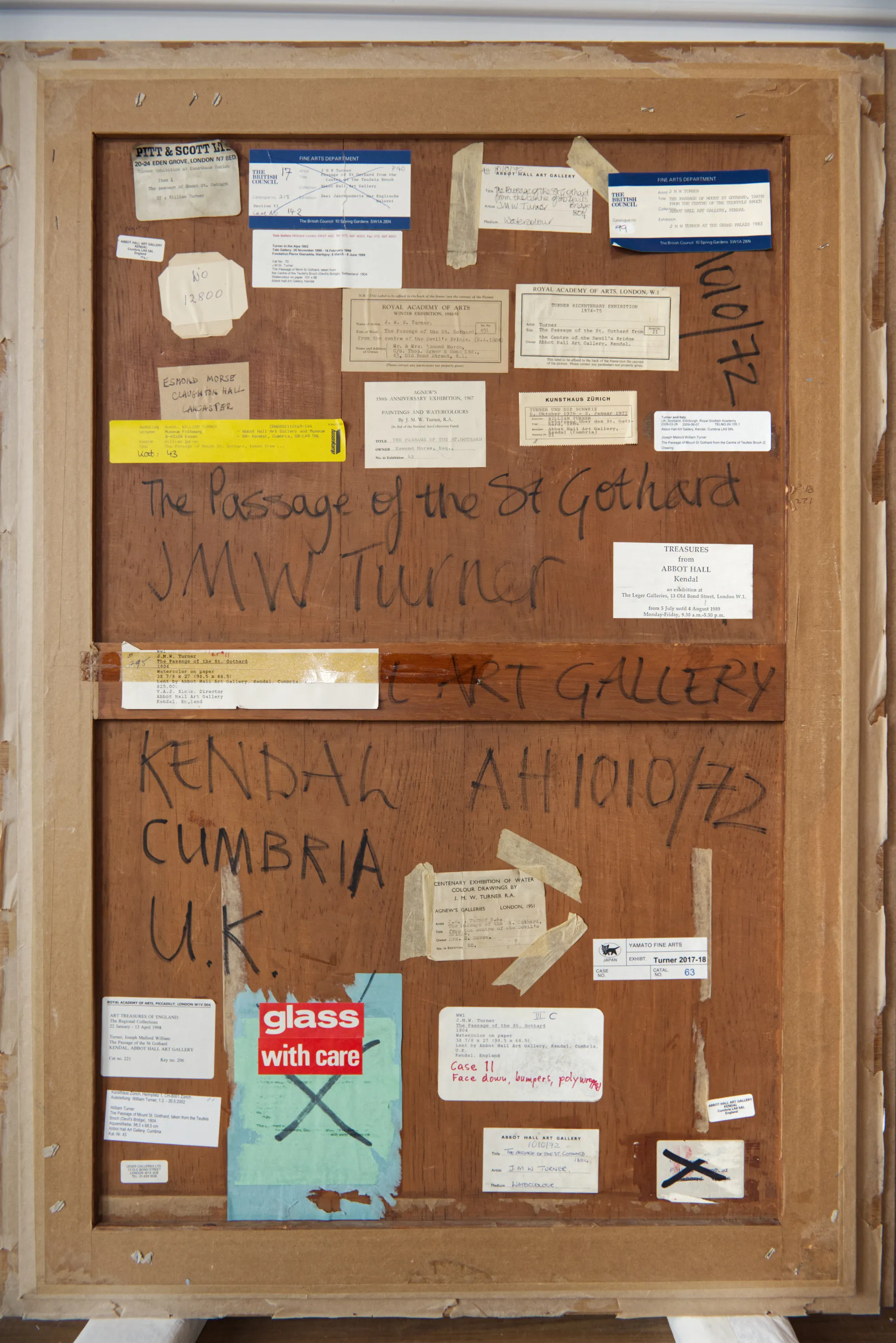 The back of a picture frame covered in exhibition labels and handwritten inscriptions