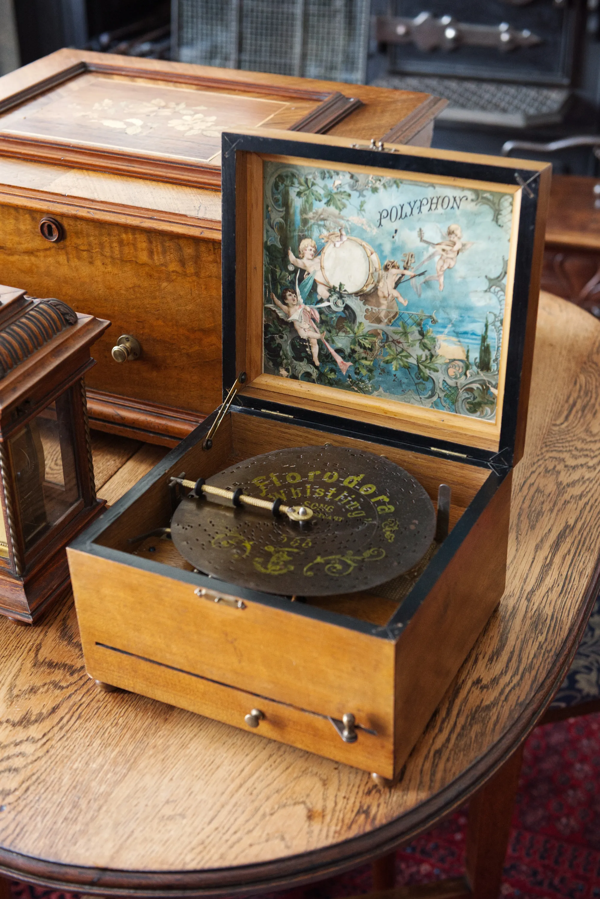An open antique music box with a decorative cherub illustration on the inside lid and a metal disc on the turntable