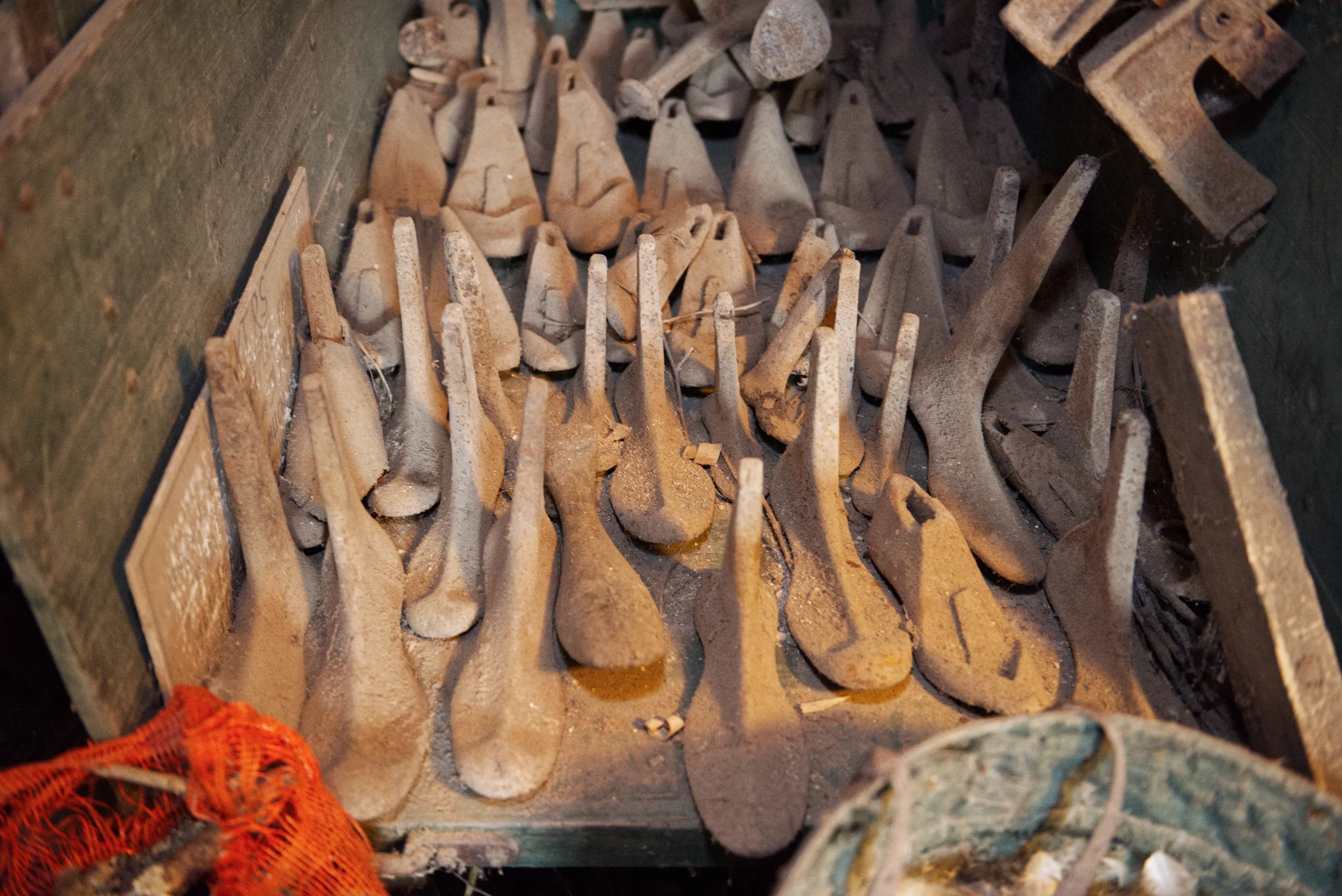 Dozens of dust-coated cast-iron shoe lasts of various sizes packed into a wooden crate