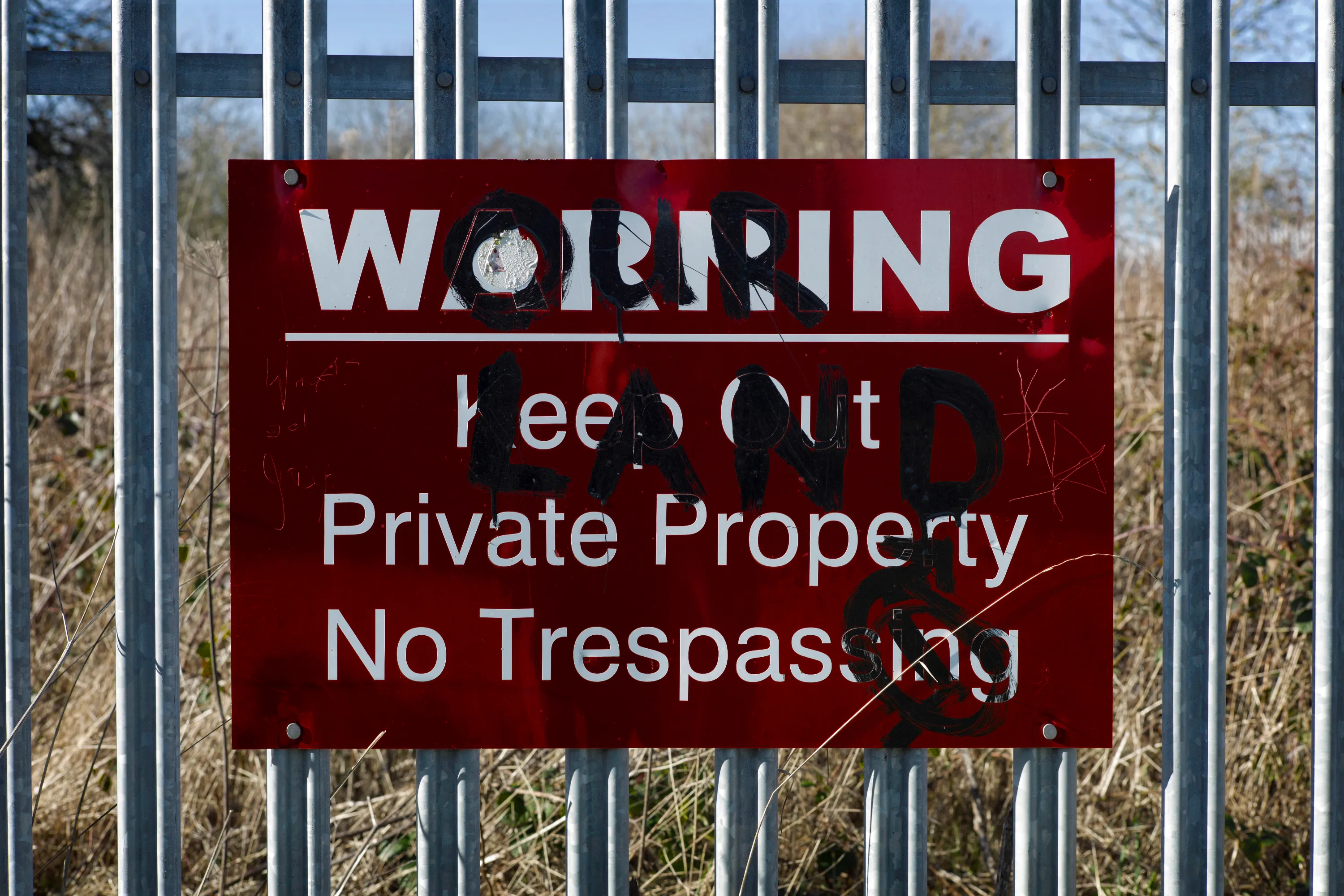 Red Warning — Keep Out, Private Property, No Trespassing sign with graffiti overwritten