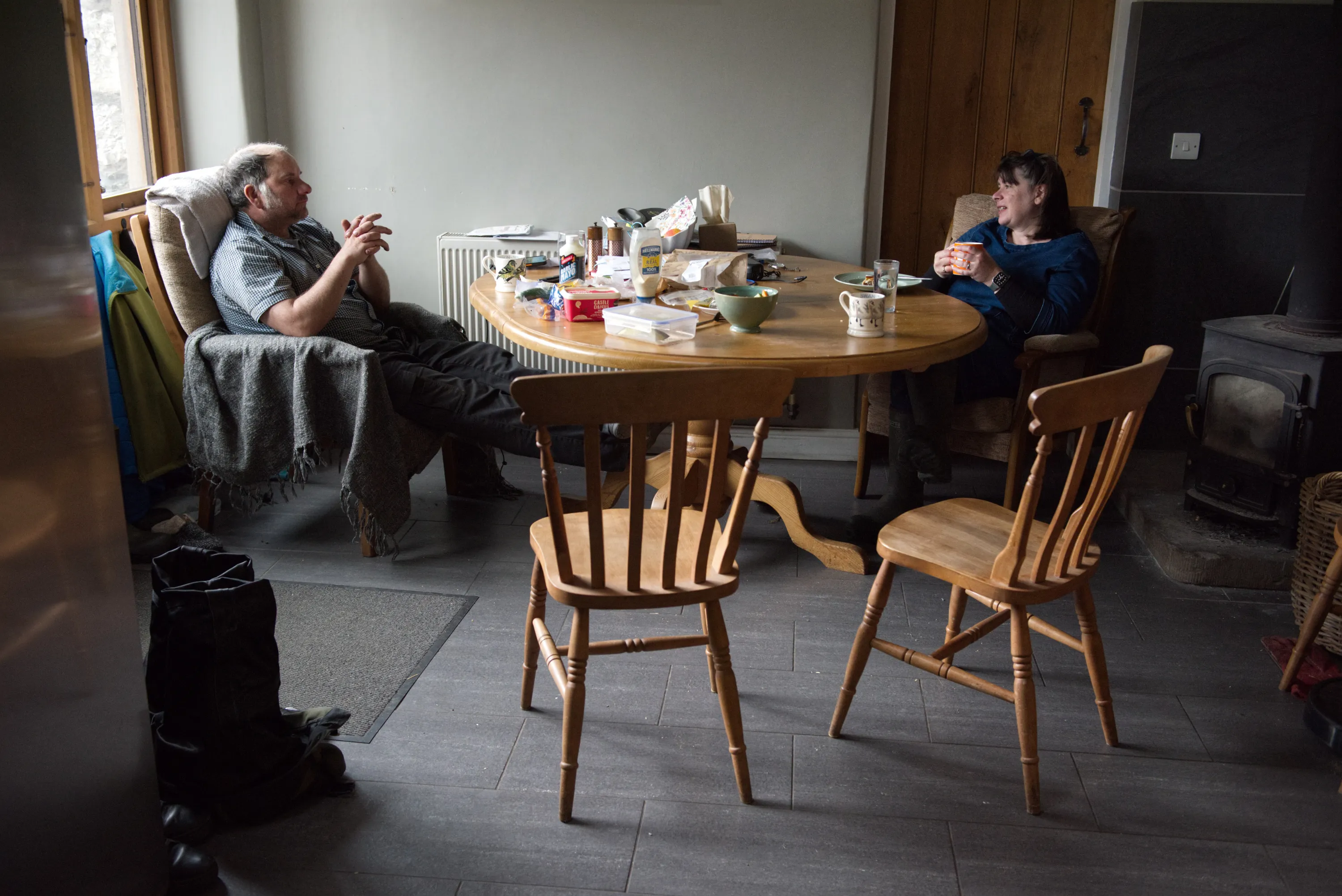 Man and woman seated at a round wooden kitchen table talking