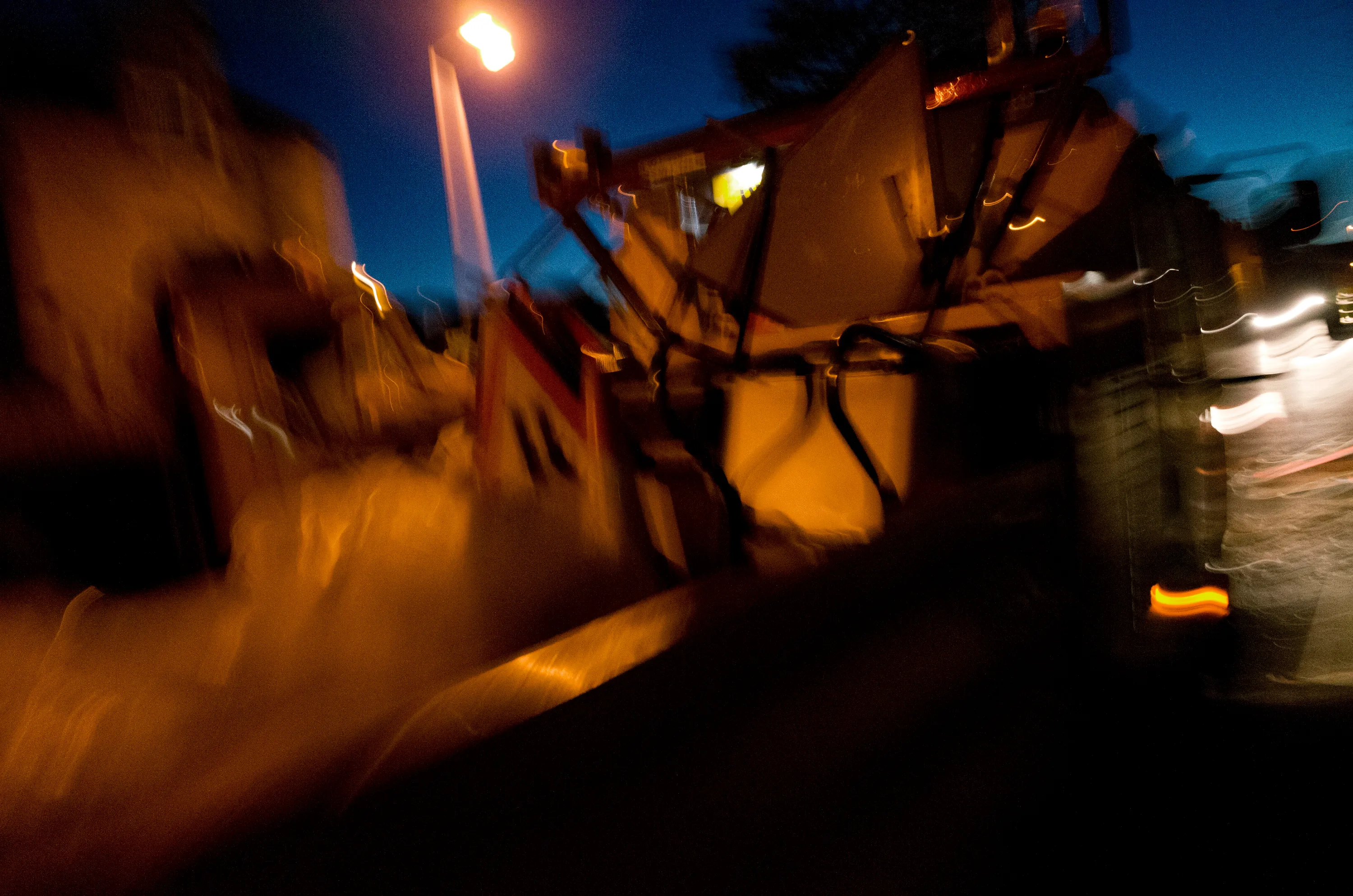 Blurred yellow construction machinery on a dark street at night