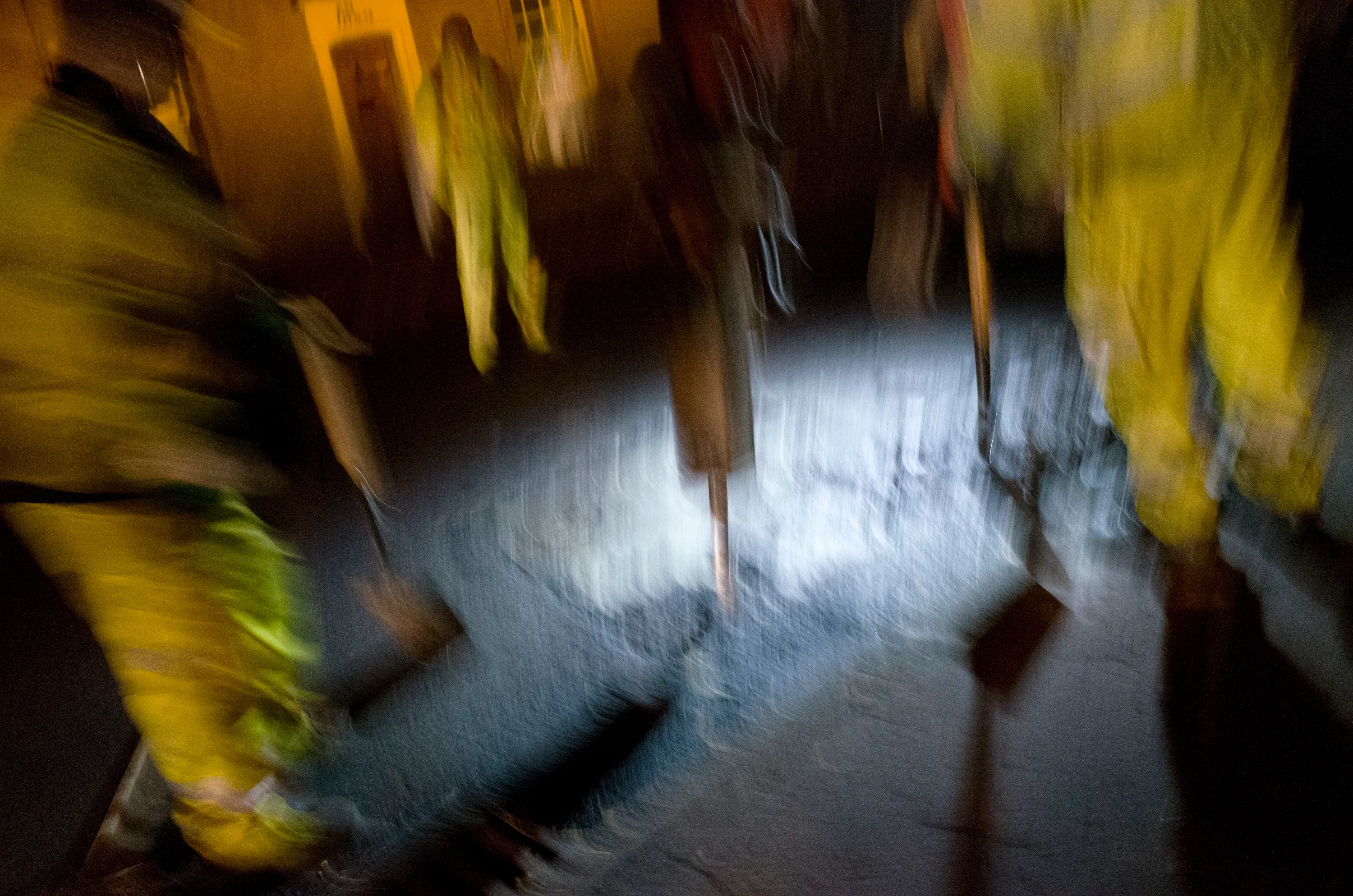 Blurred figures in high-visibility jackets on a wet pavement at night