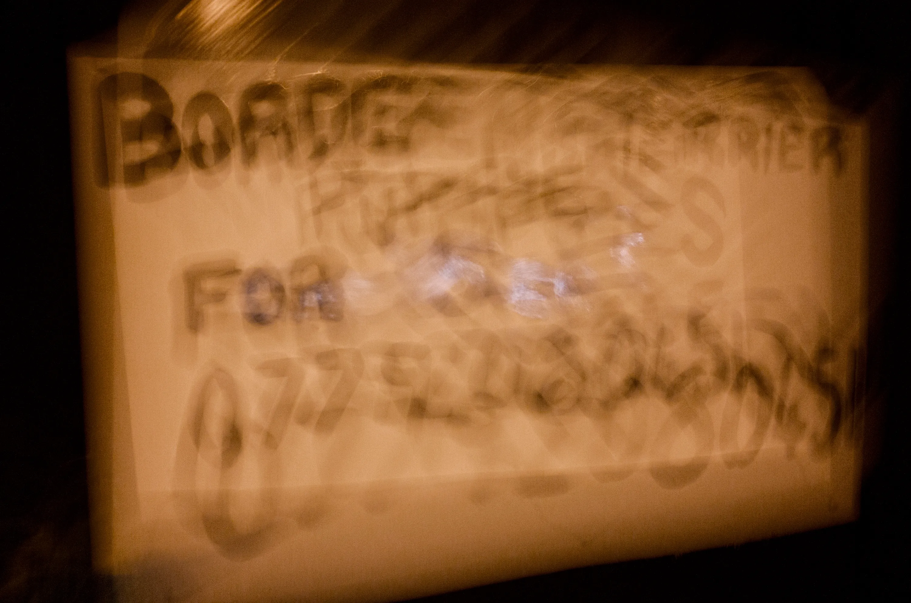 Motion-blurred handwritten sign reading Border Terrier for sale with phone number