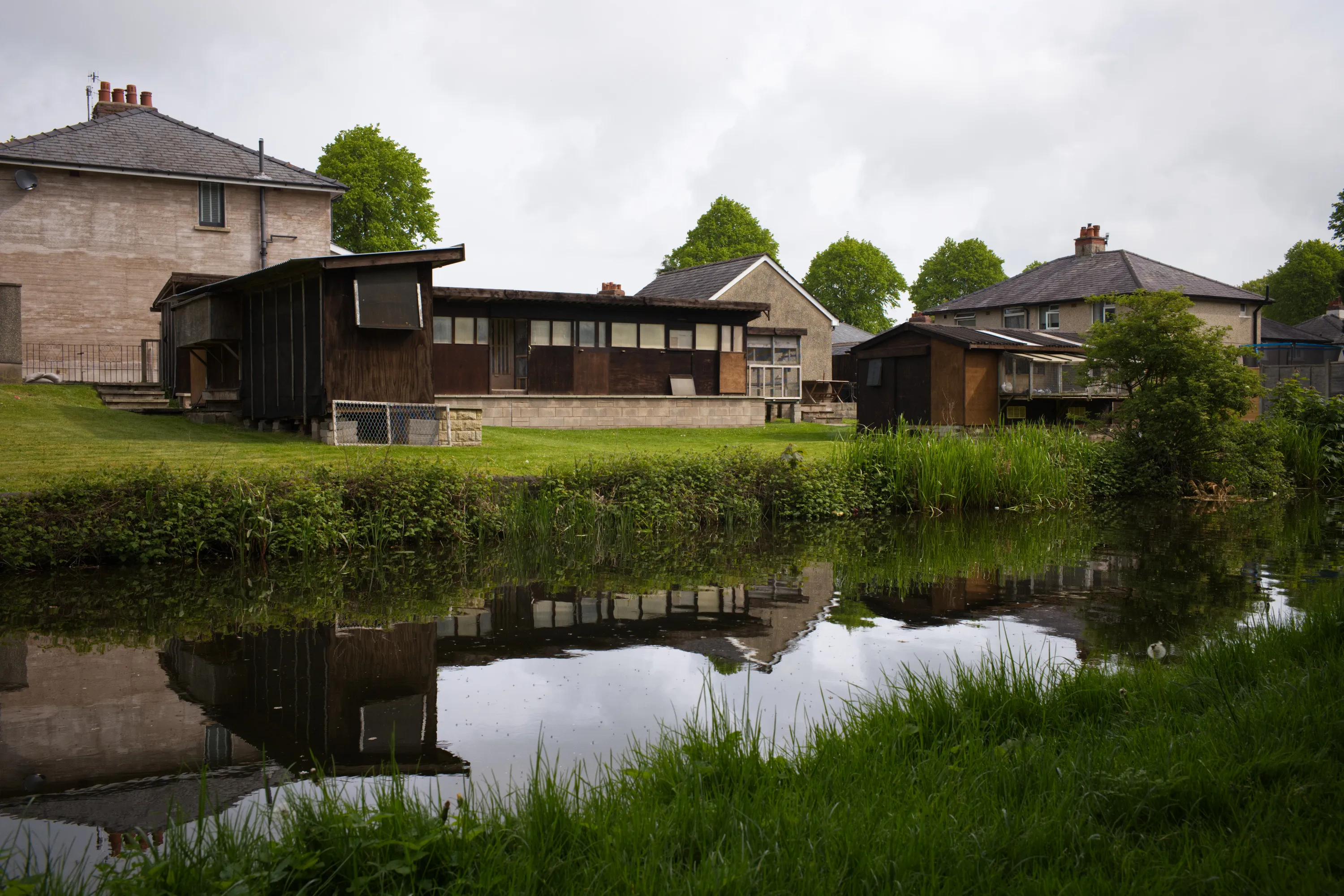 Wooden pigeon loft reflected in a still canal, houses behind