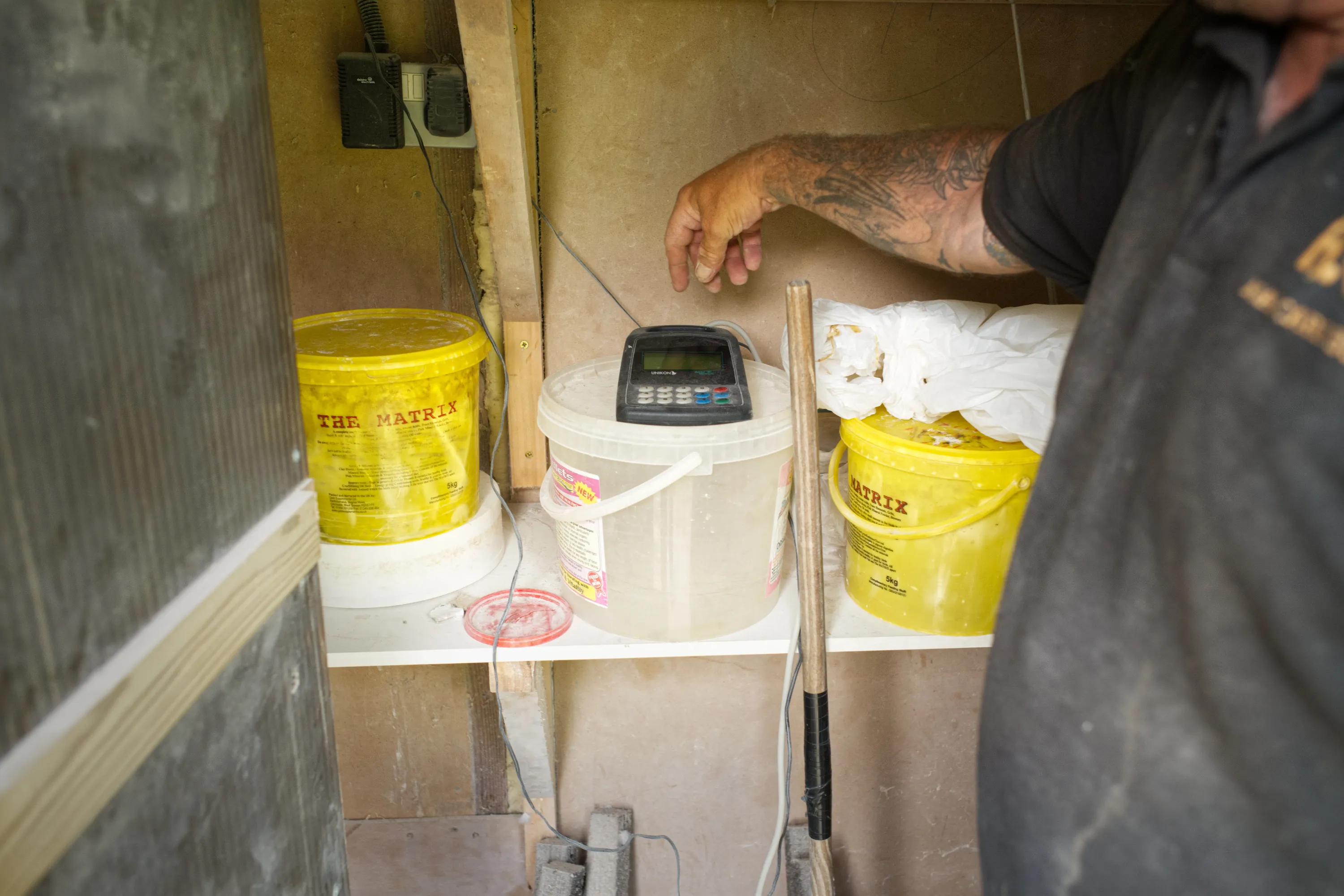 Tattooed hand adjusting an electronic timing device among yellow buckets
