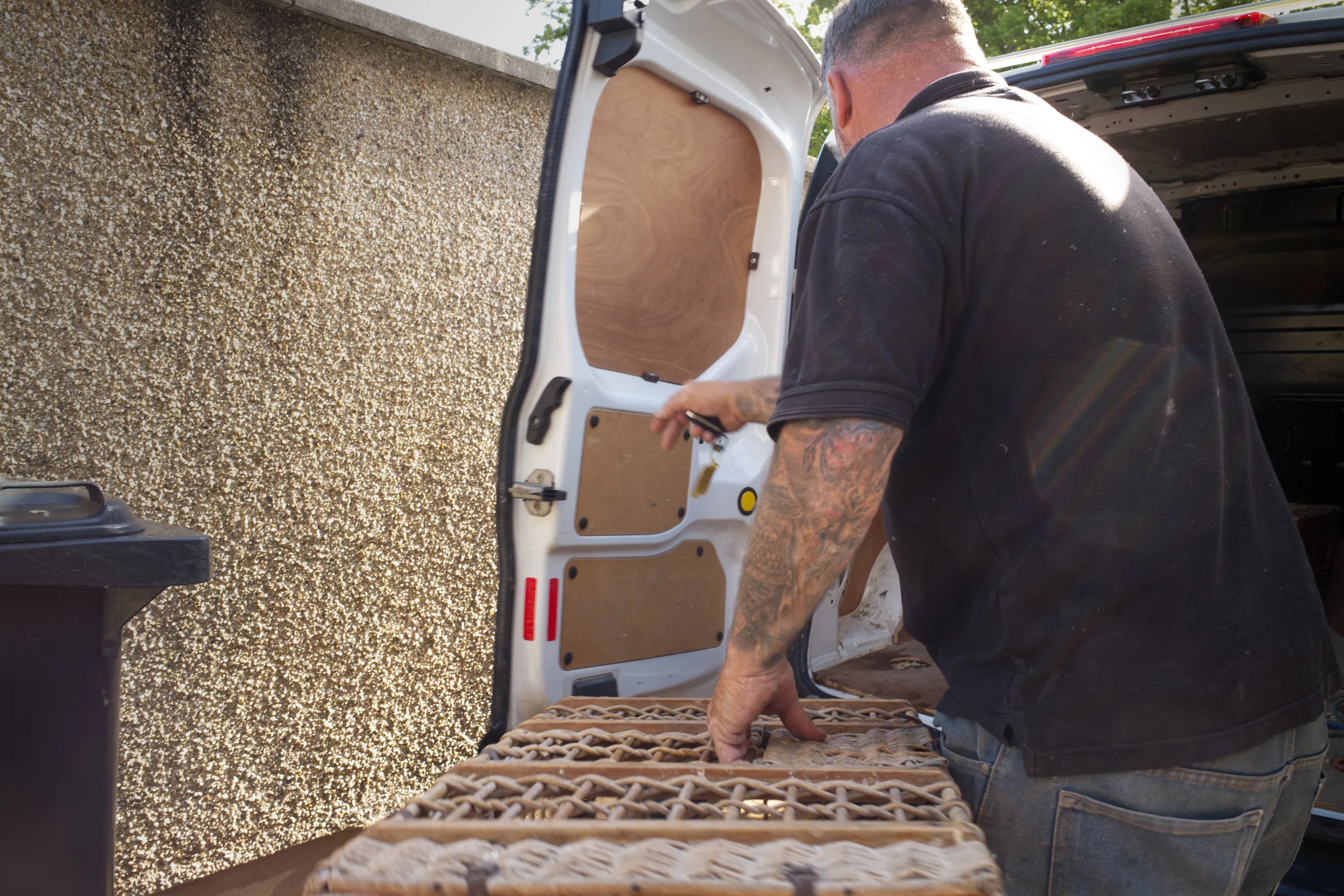 Man loading wicker pigeon baskets into the rear of a white van