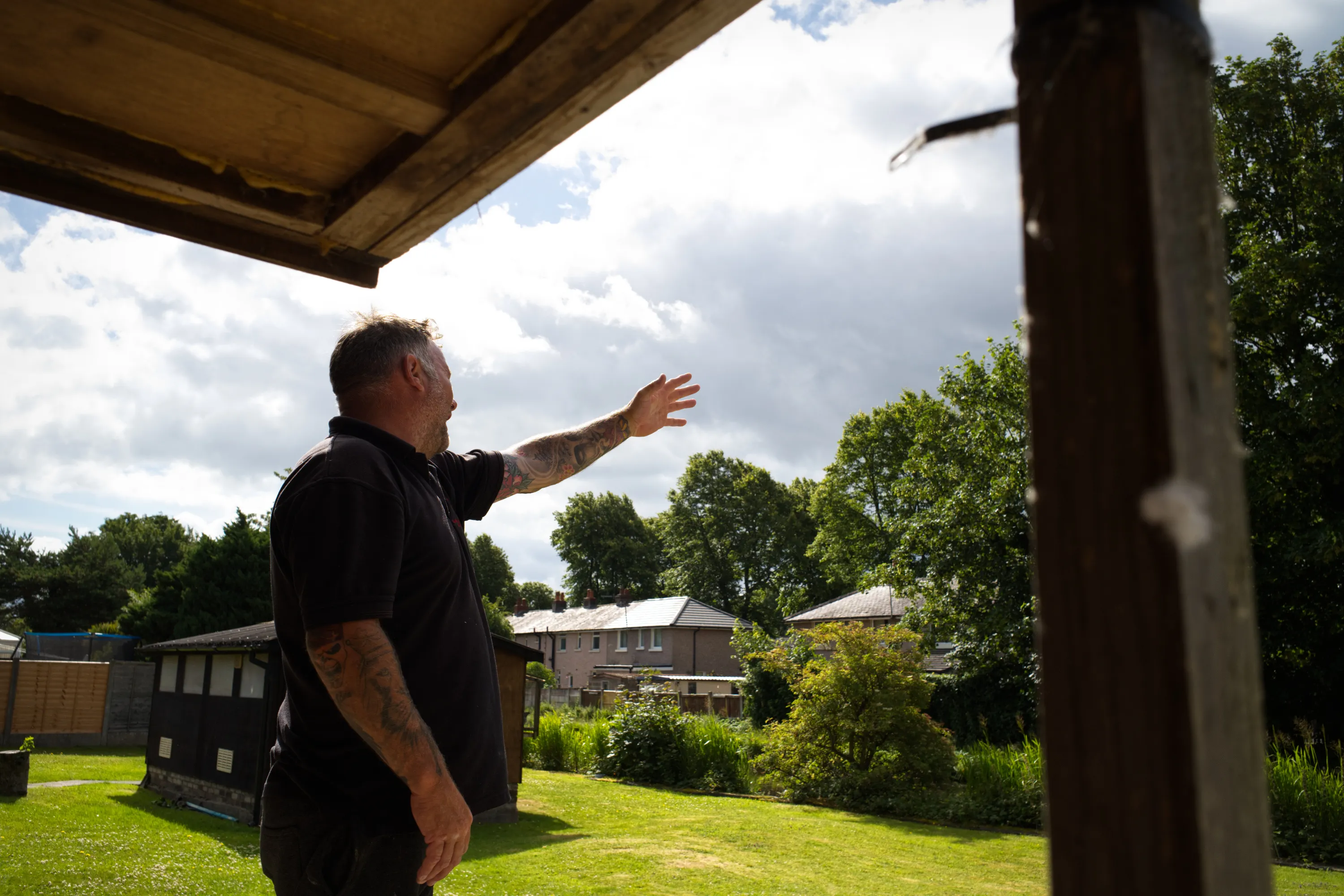 Man beneath a loft overhang reaching one arm out toward the sky