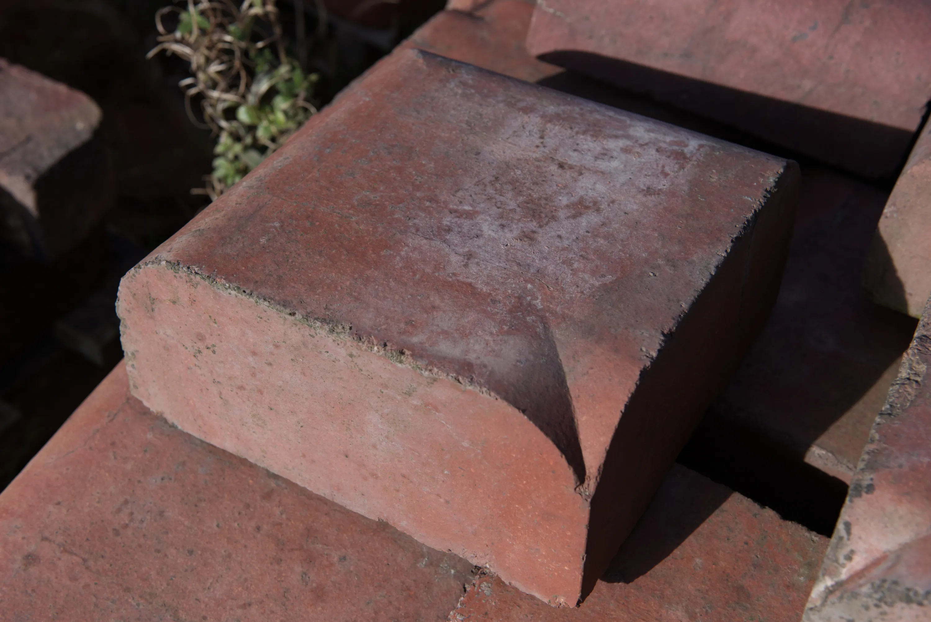 A single large chamfered red brick on top of a stack, casting a strong shadow