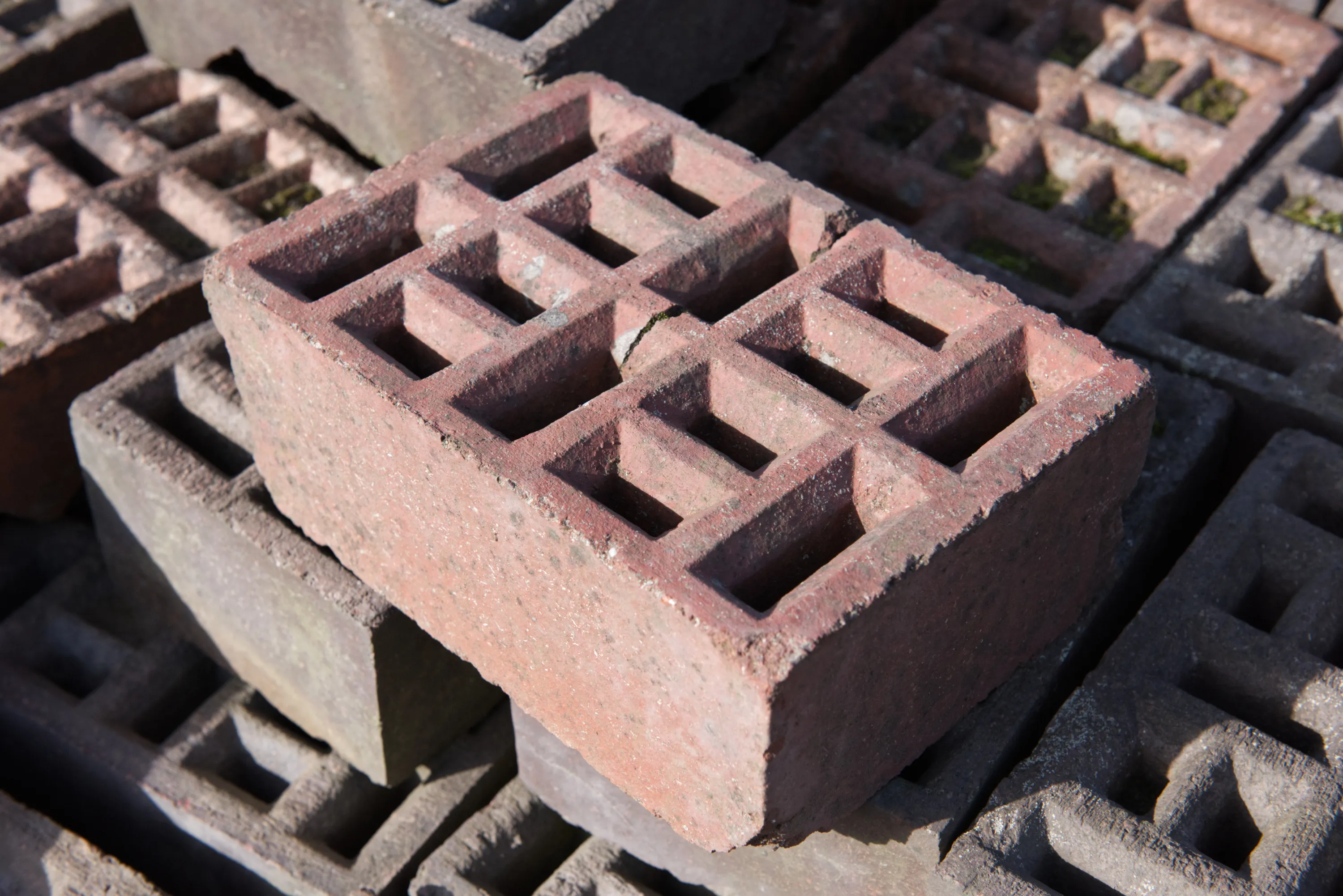 Close-up of a red brick with a grid of square perforations across its top face