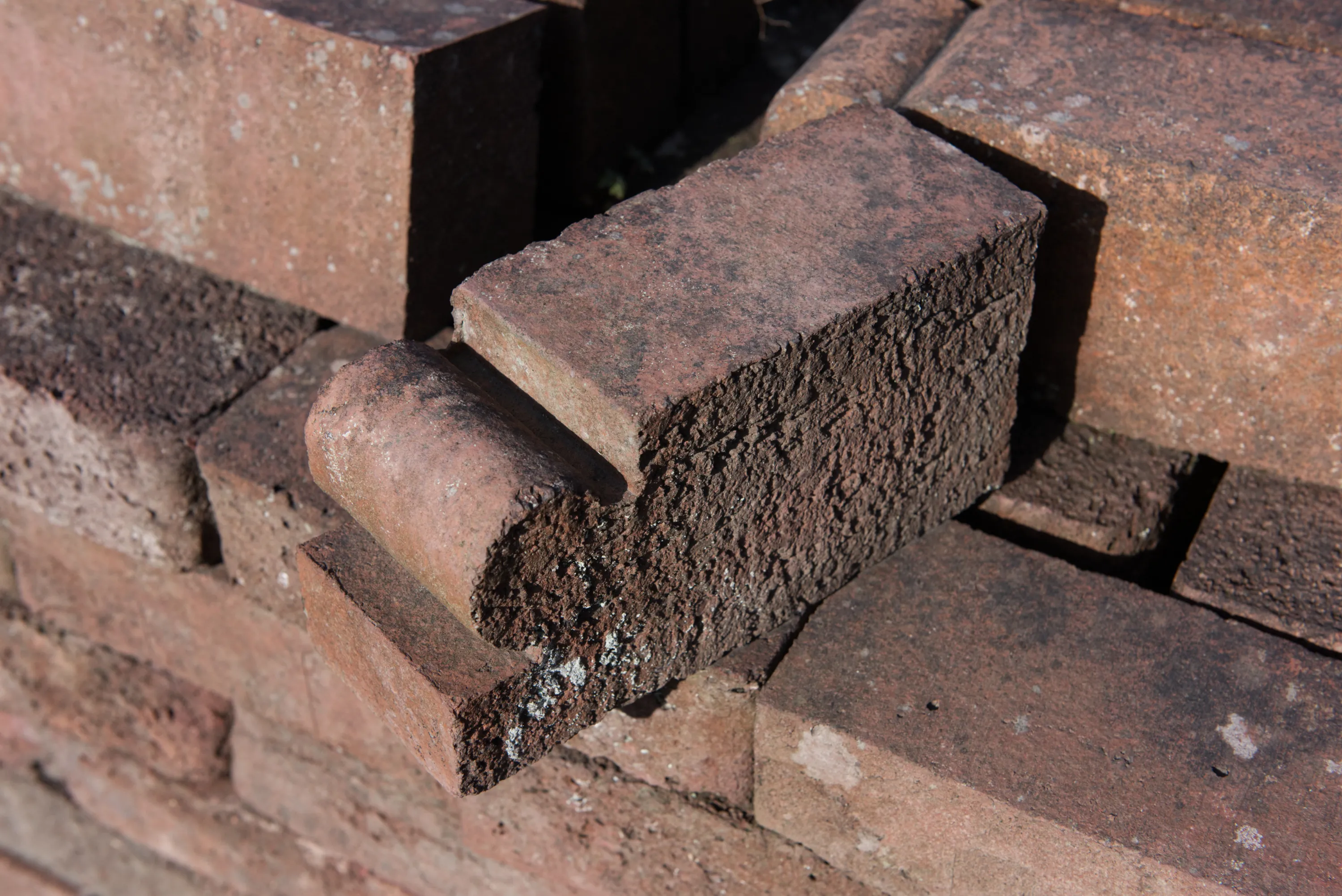A split or broken red brick resting among other bricks, revealing a rough dark interior