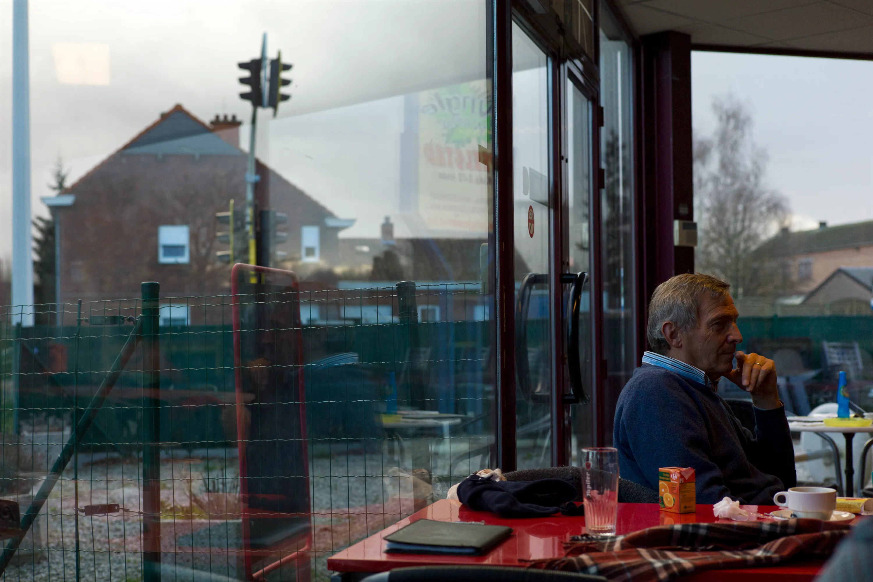 Man seated alone at a café table by a large window
