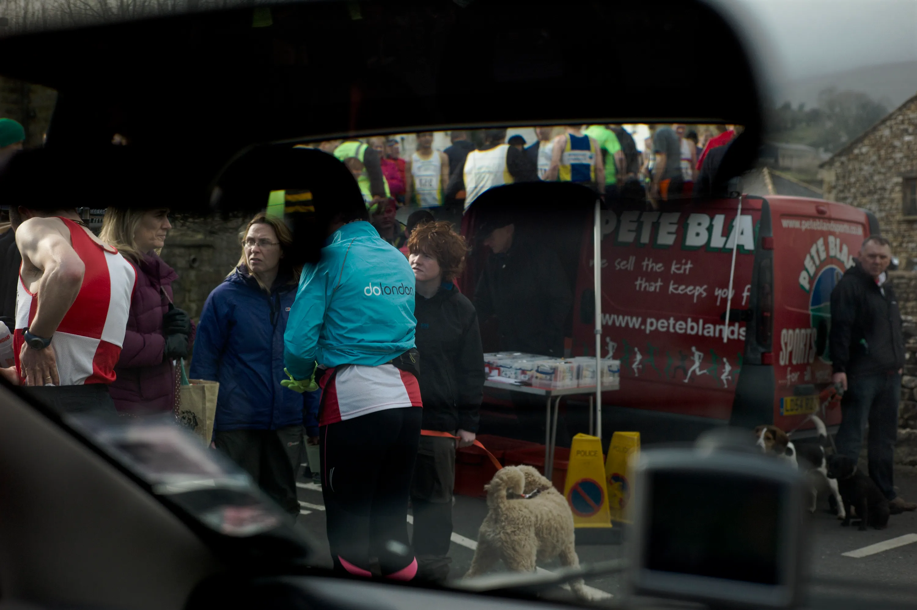 Runners and bystanders gathered at a road race, viewed through a car windscreen