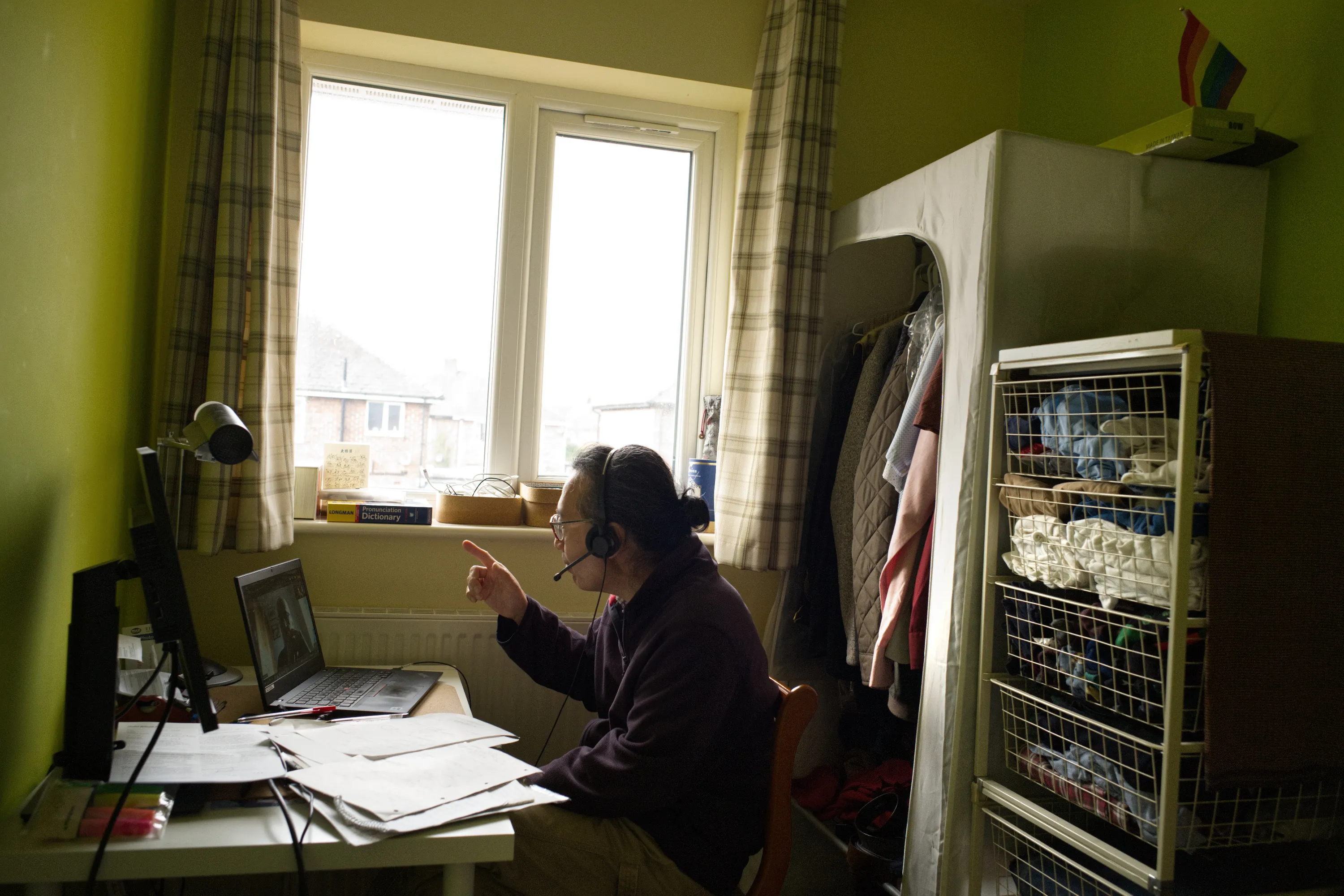 Person wearing a headset gesturing at a screen in a green-walled bedroom